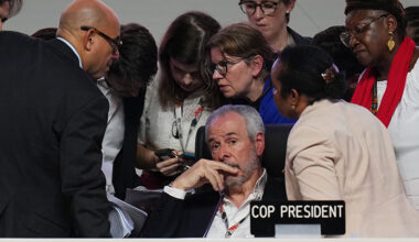 De står runt honom. Han sitter ned.