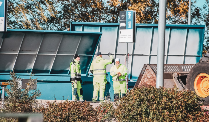 Tre återvinningsarbetare på en återvinningscentral