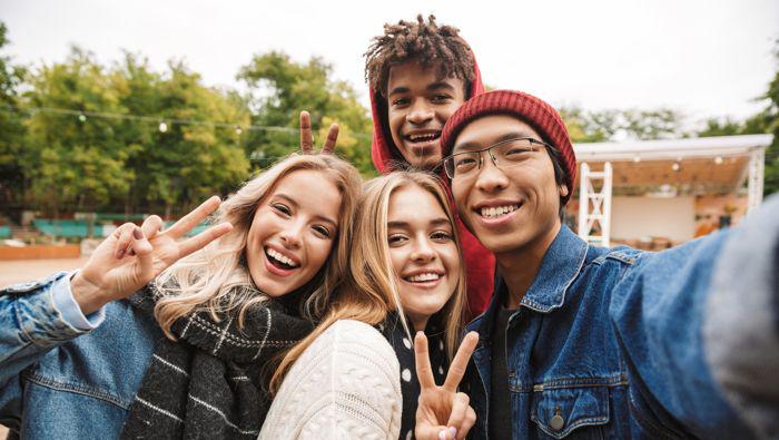 Två tjejer och två killar i tonåren ler mot kameran.