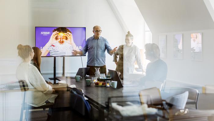 Två personer har en presentation för andra vid ett bord
