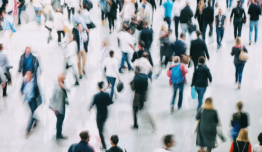 Suddig bild av många människor som går över ett torg eller liknande plats.