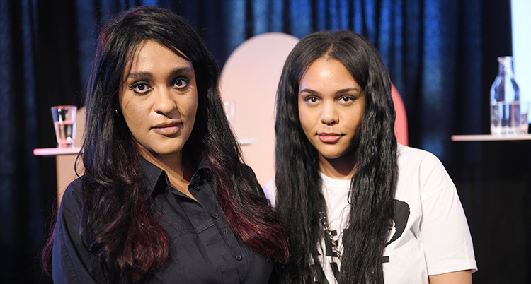 Två kvinnor med långt hår. De står bredvid varandra och tittar in i kameran.