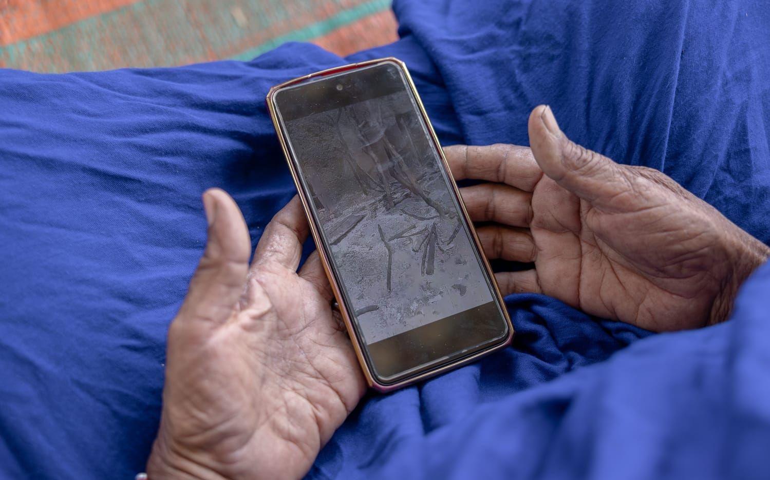 Maliska Afay visar bilder på den brända hembyn efter att legosoldater från Afrikakåren lagt byn i ruiner. Bild tagen i Douankara i grannlandet Mauretanien i november.