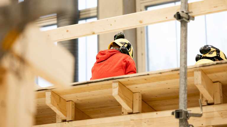 Byggarbetare jobbar vid byggställning. 