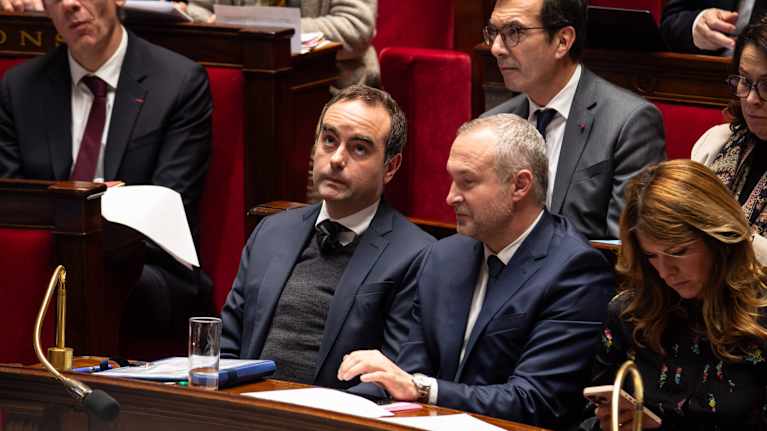 Två män och en kvinna sitter i en sal med röda plyschsäten.