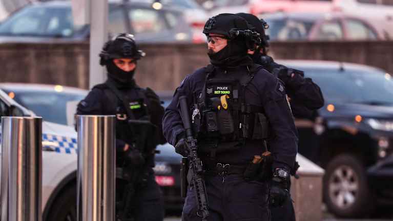 Tre beväpnade poliser bevakar området kring Bondi Beach. 