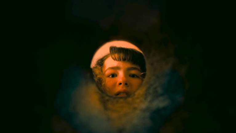 En ung flicka med skräckslagen blick kikar in i ett rör i serien IT Welcome to Derry. 