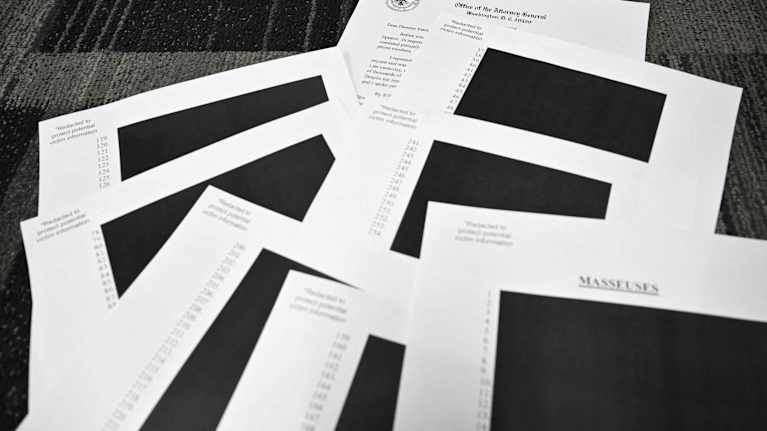 Helt svärtade dokument ligger på en matta. 