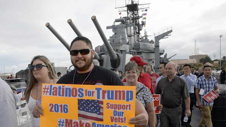 Människor med kampanjskyltar framför det avställda slagskeppet USS Iowa.