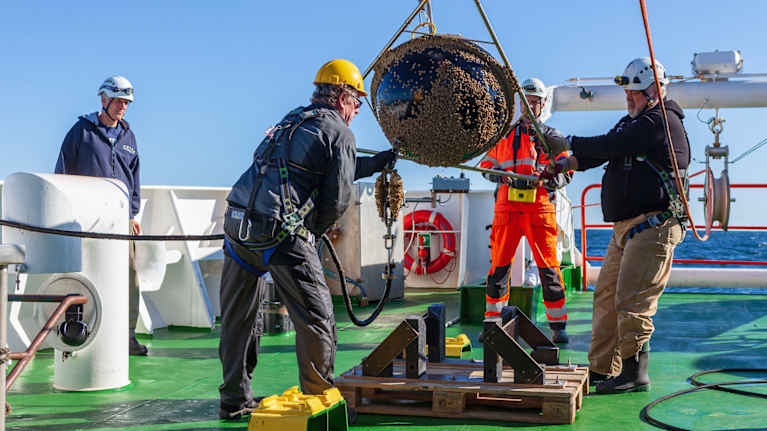 Forskare på Aranda hanterar en vågboj på däck.