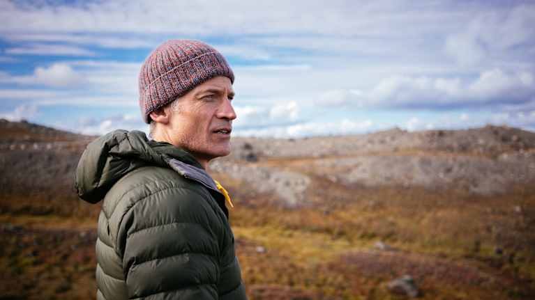 En man står och tittar ut över ett arktiskt landskap.