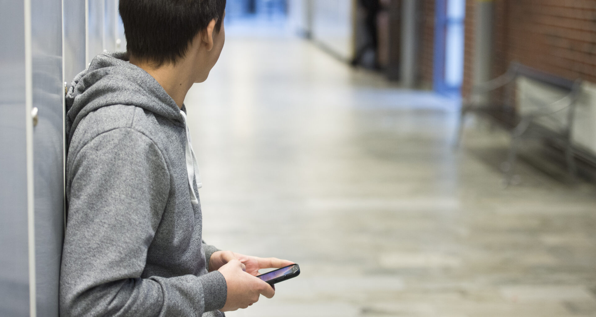 Ung man i täckjacka tittar på sin mobiltelefon.