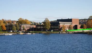 vy över en stor röd byggnad med vatten i förgrunden. intill byggnaden går ett grönt streck