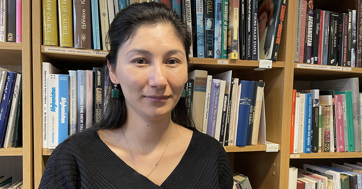 Kvinna framför en bokhylla.