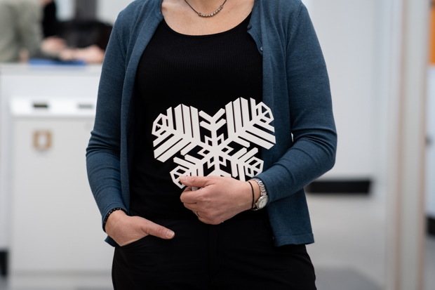 person som håller i ett vitt östersundshjärta, som är som en snöflinga format som ett hjärta