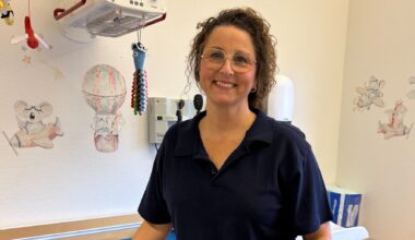 En kvinna i vårdklädsel står vid ett undersökningsbord för små barn.