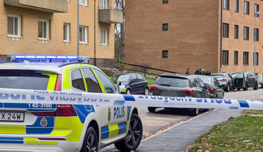 Poliser på en gata framför hus med lägenheter.