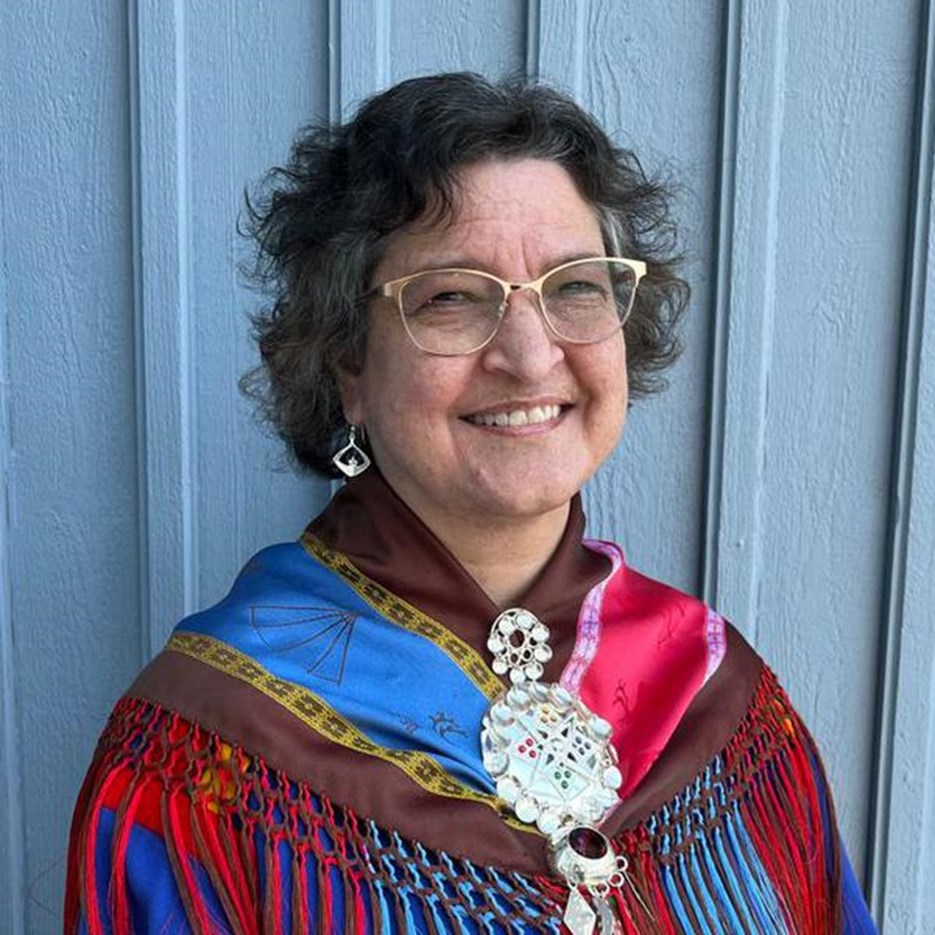 En kvinna med glasögon och en färgglad sjal.