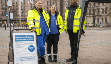 Tre personer står på ett torg utomhus.