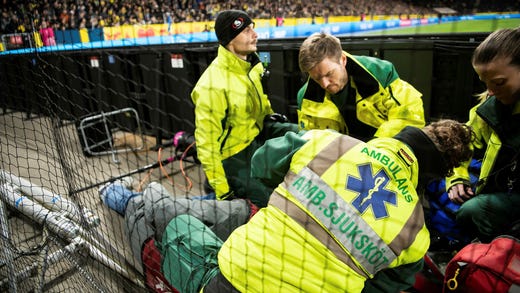 Sjukvårdare tar hand om fotografen Maxim Thoré som träffats av en inkastad stol.