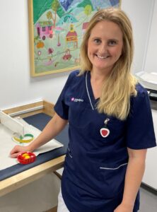 En kvinna i vårdklädsel står vid ett undersökningsbord för små barn.