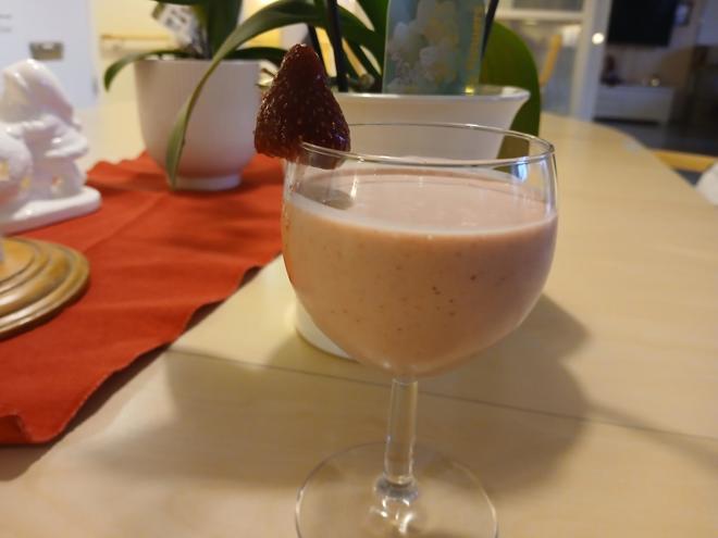 Glas på fot med tjock, rosa dryck.