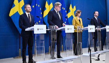 Fyra personer står vid varsitt bord. De har varsin mikrofon. Bakom dem finns Sveriges flagga och EUs flagga.