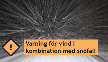 Svartvit bild med snö som yr. En varningsskylt samt texten "Varning för vind i kombination med snöfall".
