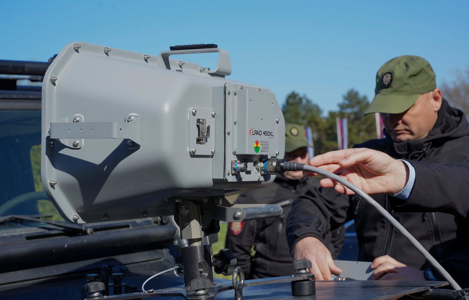 Serbiskt gendarmeri visar en USA-tillverkad ljudkanon (LRAD) som enligt serbiska demonstranter användes mot dem i fjol. Bild tagen 19 mars 2025.