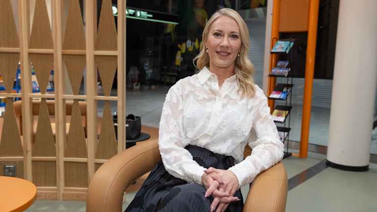 Mona Moisala sitter i en stol och tittar i kameran.