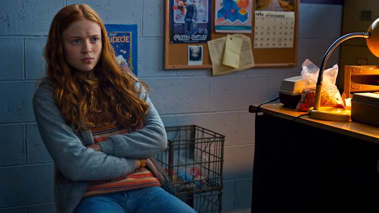 Ung rödhårig tjej sitter besvärat på en stol på ett kontor.