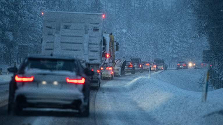 En lång bilkö i ett snöoväder.