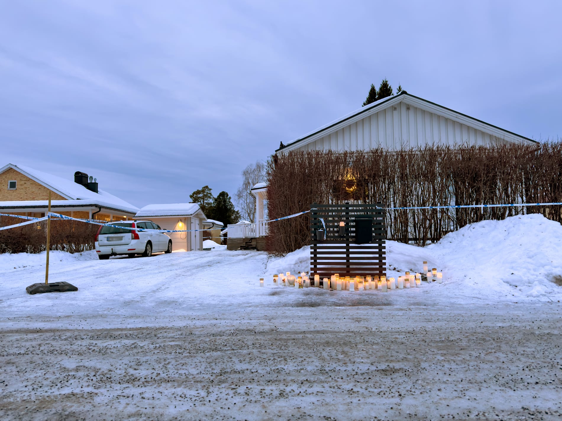 Ljus placerade utanför det hus i Boden där en 55-årig kvinna blev mördad och hennes två tonårsdöttrar blev skadade på juldagen.