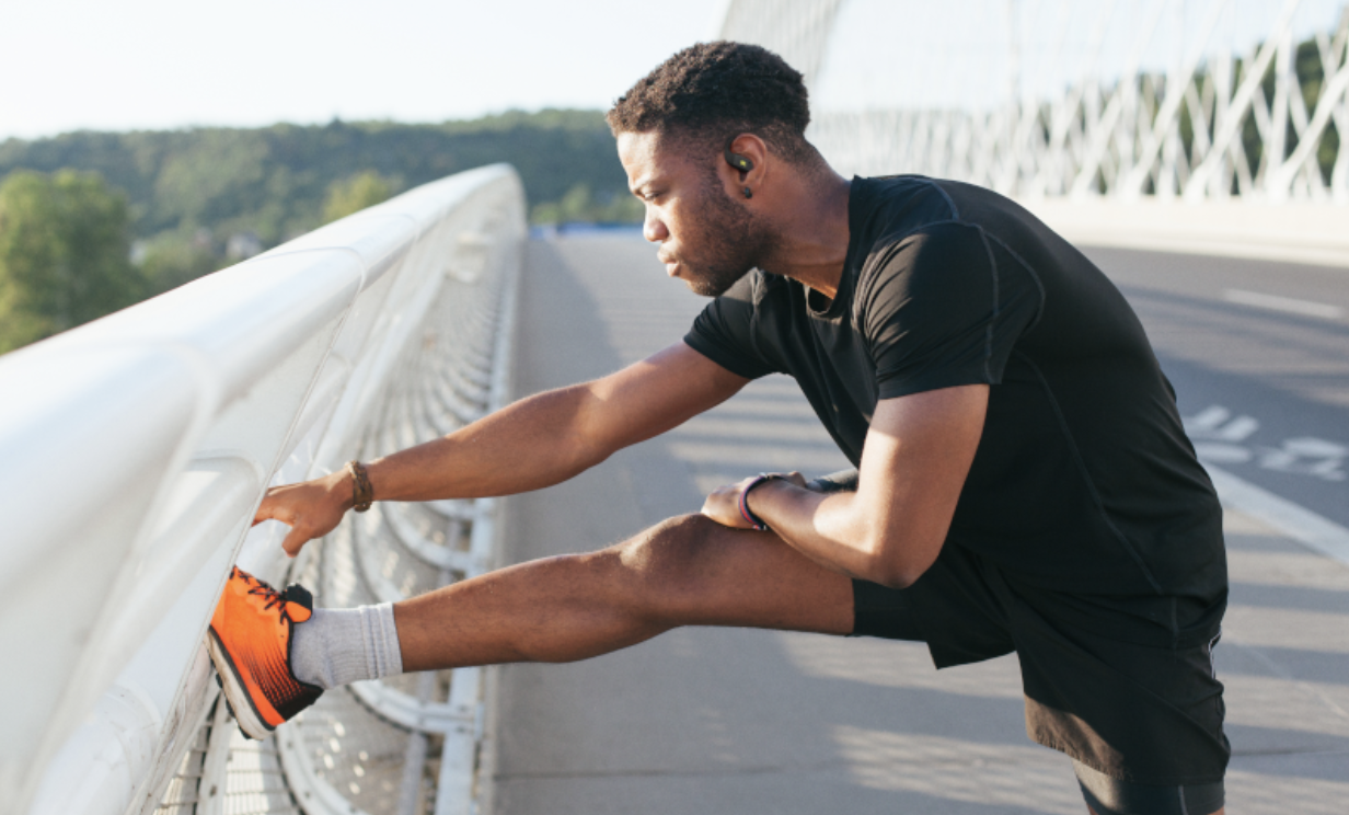 JBL Endurance Peak 4 anv&auml;nds av en l&ouml;pare som st&aring;r och stretchar p&aring; en bro.
