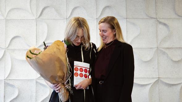 Två glada kvinnor med blommor och avhandlingen