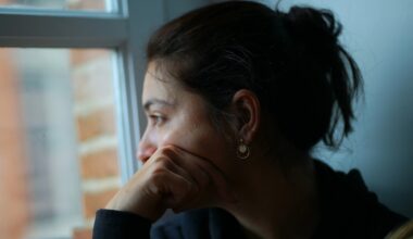 Tankfull kvinna med mörkt hår i en tofs tittar ut genom ett fönster.