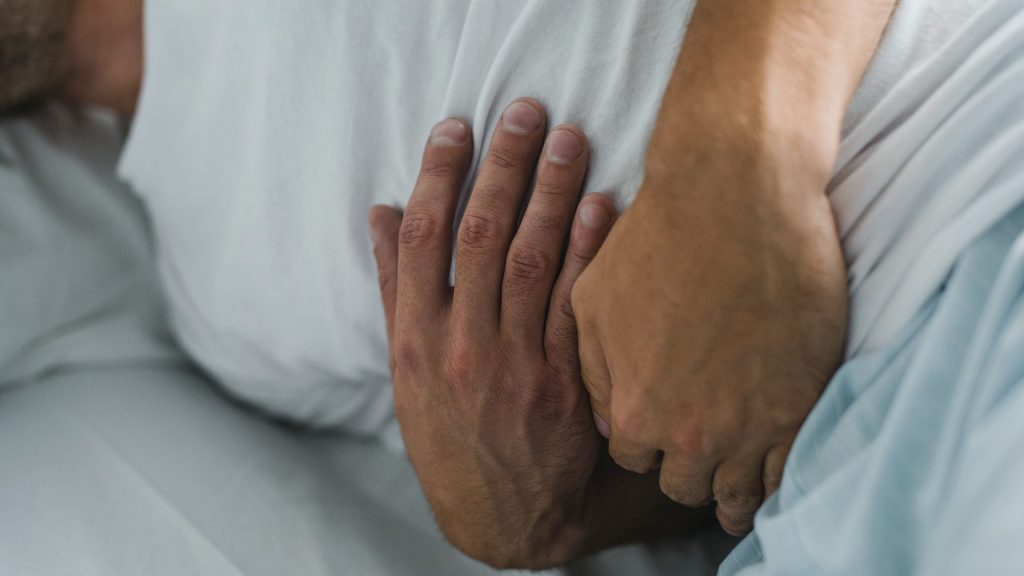 Man ligger i sängen och håller om magen.