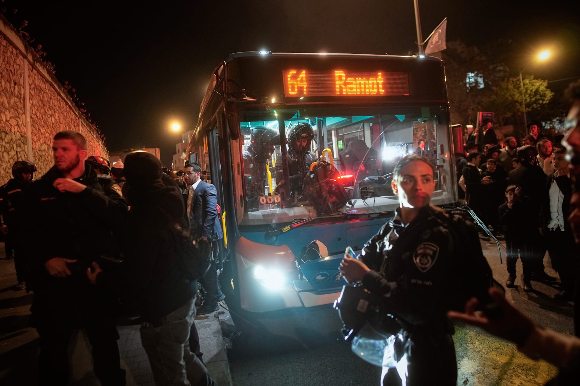 Israelisk polis undersöker en buss som kört på demonstranter i Jerusalem.