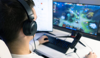 Tonårskille med hörlurar sitter framför datorskärm och spelar.