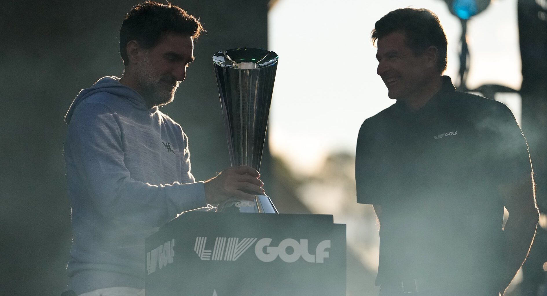 två män vid ett podium och en pokal