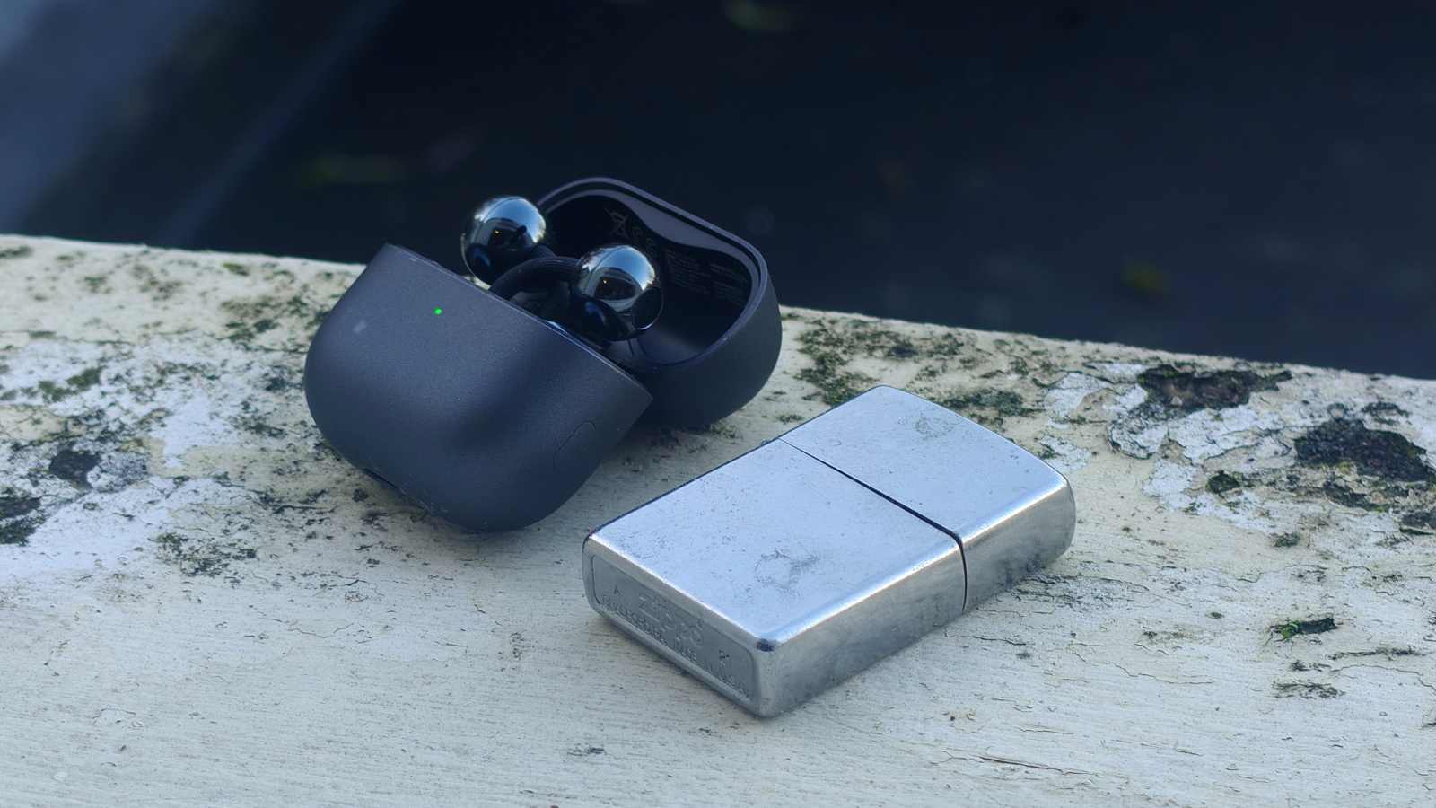 Huawei FreeClip 2 i sitt laddningsfodral, bredvid en t&auml;ndare.