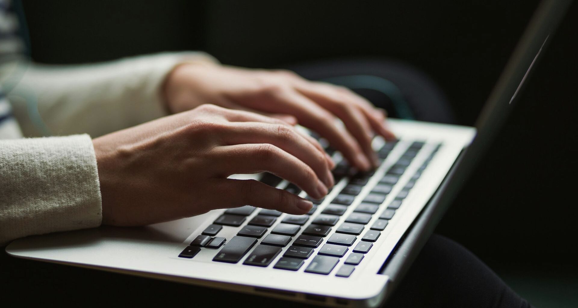 Händer nuddar tangentbord på bärbar dator.