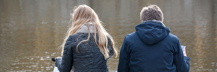 Tjej och kille sitter vid havet.