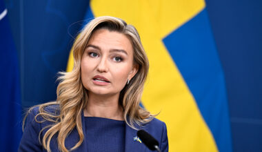 Hon står framför svenska flaggan.