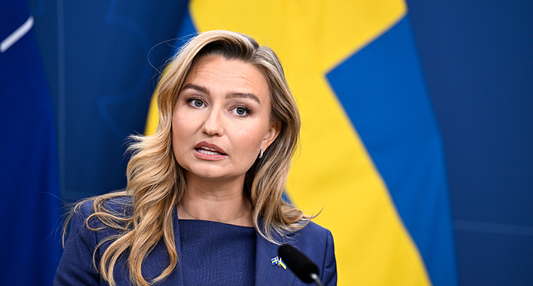 Hon står framför svenska flaggan.