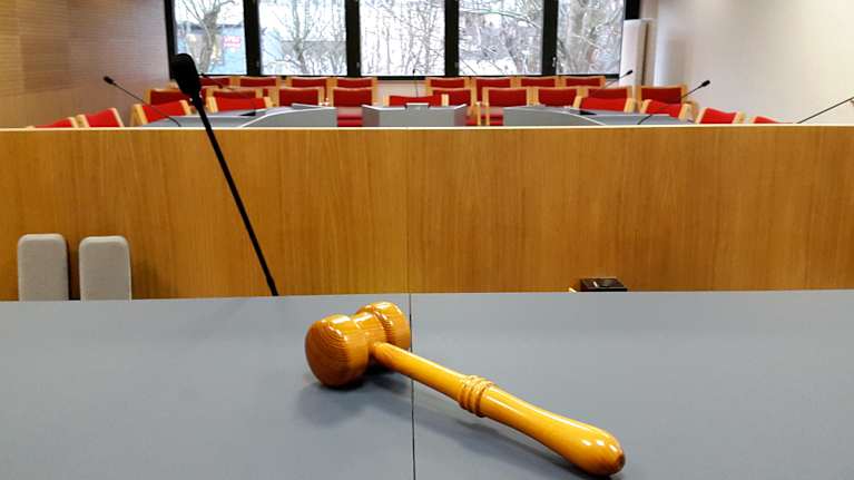 En rättssal, bilden tagen från domarens perspektiv. I förgrunden en domarklubba.