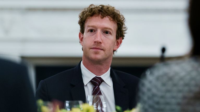 Mark Zuckerberg i en mörk kostym sitter vid ett bord och tittar åt sidan.