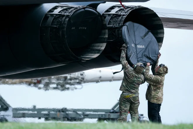Pripadniki zemeljske posadke nameščajo zaščitni pokrov motorja na bombnik B-1 ameriških zračnih sil v letalski bazi RAF Fairford v Veliki Britaniji med zaostrovanjem konflikta med ZDA, Izraelom in Iranom.  FOTO: Phil Noble Reuters