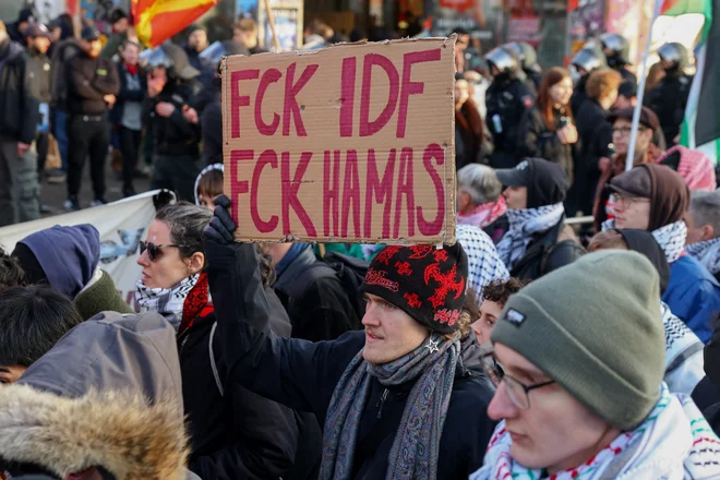 Na fotografiji s propalestinskih demonstracij, ki so potekale 17. januarja 2026 v nemškem Leipzigu, udeleženec protesta drži transparent s sloganom, usmerjenim proti obema stranema v spopadu – tako proti Izraelskim obrambnim silam (IDF) kot proti gibanju Hamas. FOTO: Christian Mang Reuters
