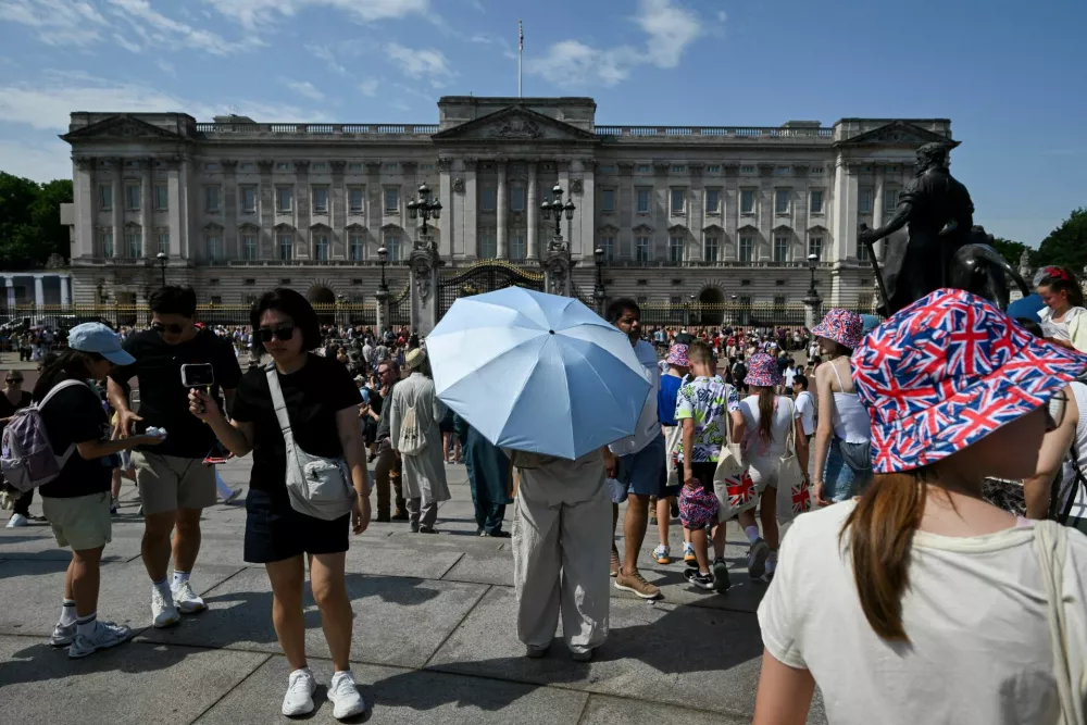A person holds an umbrella to shield from the sun outside Buckingham Palace after it was announced that Britain's King Charles will not live there after its 10-year refurbishment finishes next year, amid a heatwave in London, Britain, June 26, 2026. REUTERS/Jaimi Joy TPX IMAGES OF THE DAY